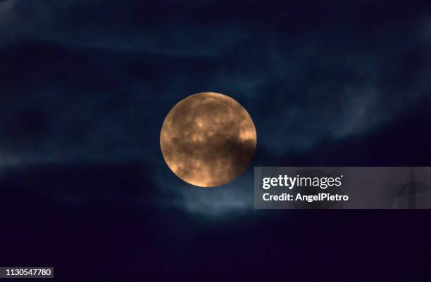 full moon half hidden behind the clouds during the early morning - cielo dramático stock pictures, royalty-free photos & images