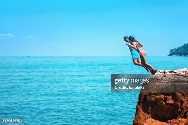 family enjoying on summer vacation, they jumping from the cliff into blue sea - cliff dive stock pictures, royalty-free photos & images