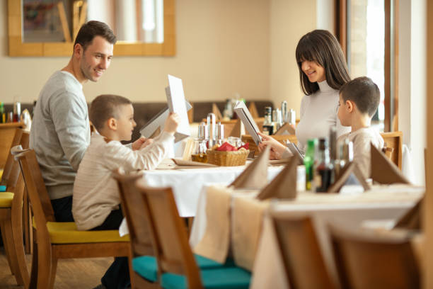 family at lunch in hotel restaurant -  family restaurant menu stock pictures, royalty-free photos & images