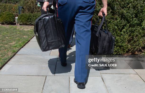 Military aide to US President Donald Trump carries a briefcase known as the "nuclear football" through the Rose Garden of the White House in...