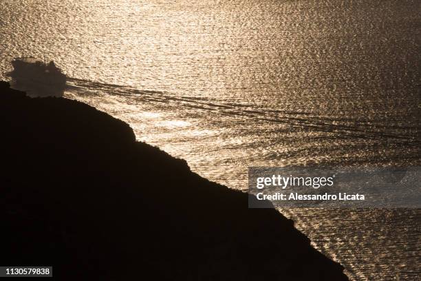 sea ​​at sunset with island and ship - idillio stock pictures, royalty-free photos & images