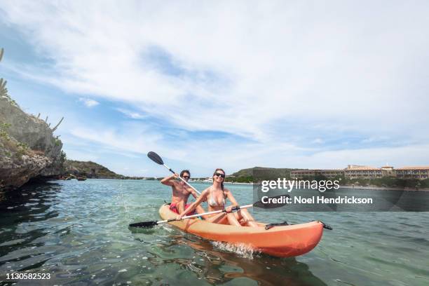 sunlit couple kayaking in the bay - curaçao stock pictures, royalty-free photos & images