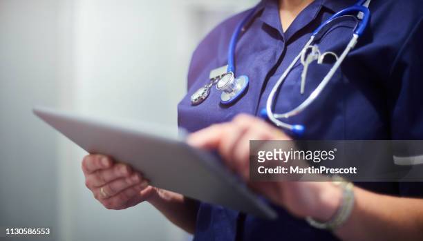 doctor or surgeon using digital tablet - uk imagens e fotografias de stock