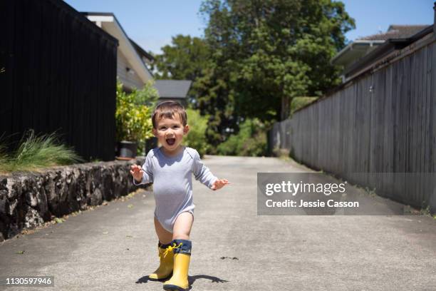 kid having fun walking outside with onesie and gumboots - auckland city people stock-fotos und bilder