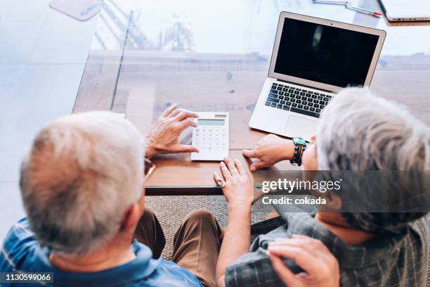 senior couple planning their retirement - calculator top view stock pictures, royalty-free photos & images