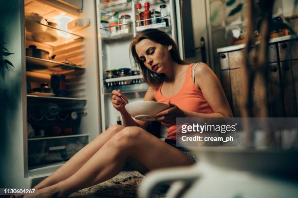 donna in pigiama davanti al frigorifero a tarda notte - weight gain foto e immagini stock