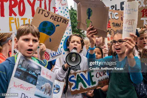 Students hold placards and shout slogans as they participate in a protest on March 15, 2019 in Hong Kong, China. Students around the world took to...