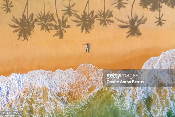 the guy lies on a sandy beach on a tropical island. drone view - shore stock-fotos und bilder