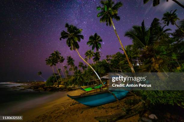 milky way over the sandy beach with boats and palm trees. sri lanka - tropical tree stock pictures, royalty-free photos & images