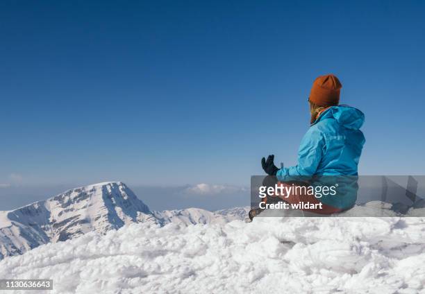 weibliche kletterer ist im winter hoch gelegenen berg meditieren. - yoga in the snow stock-fotos und bilder