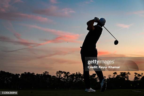 Brooks Koepka is silhouetted as he hits balls on the practice range at sunset following the first round of THE PLAYERS Championship on the Stadium...