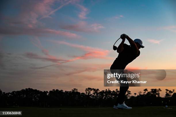 Brooks Koepka is silhouetted as he hits balls on the practice range at sunset following the first round of THE PLAYERS Championship on the Stadium...