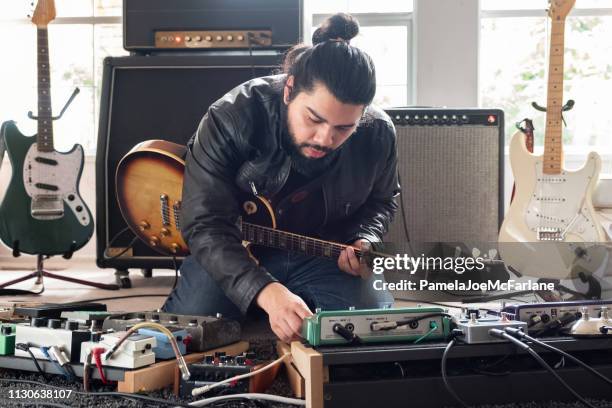 male guitarist surrounded by sound equipment adjusting sound effects pedals - sound effect stock pictures, royalty-free photos & images