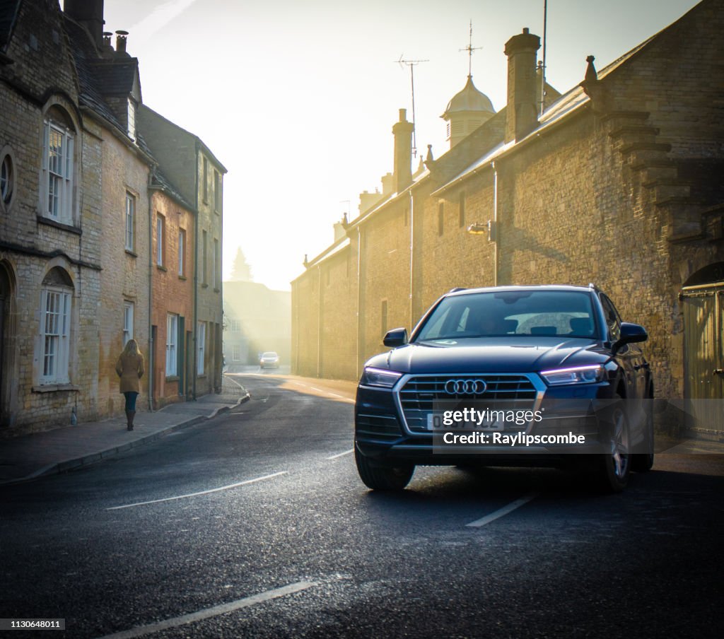 Audi Q7 4x4 car diving through the Cotswold town of Cirencester on a misty morning commute