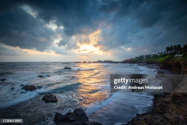 sunset with dramatic clouds over beach in bali, indonesia. - wolkengebilde foto e immagini stock