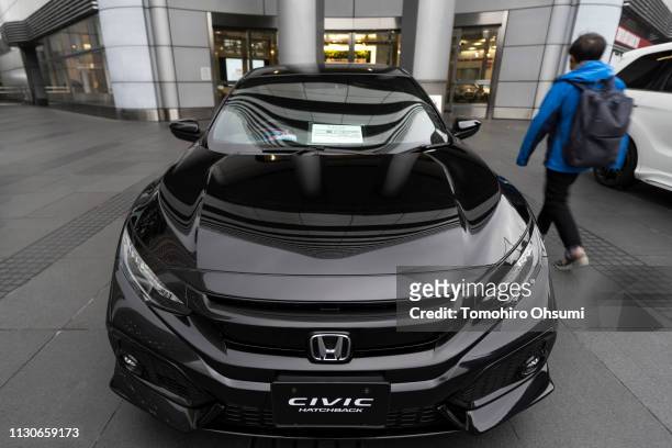 Man walks past a Honda Motor Co. Civic Hatchback vehicle displayed outside the company's headquarters on February 19, 2019 in Tokyo, Japan. Honda...