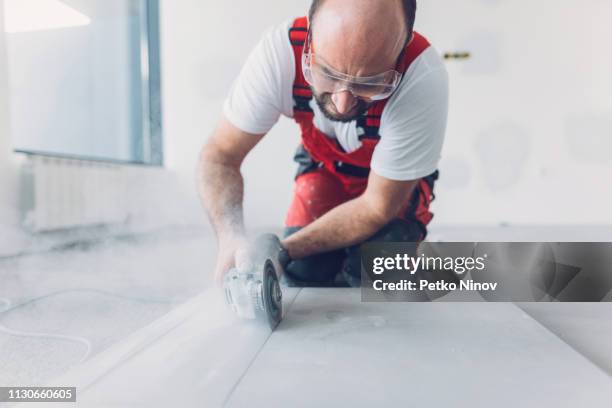 professioneller fliesenleger schneiden fliesen mit winkelschleifer - knieschützer stock-fotos und bilder