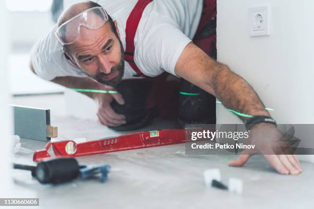 professionele bouwer meten en herverdeling van de betegelde vloer - waterpas stockfoto's en -beelden