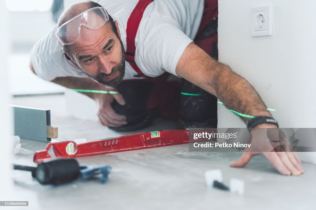 Professional builder measuring and leveling the tiled floor