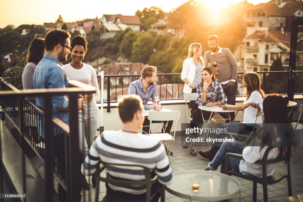 Große Gruppe glücklicher Geschäftsleute, die nach der Arbeit auf einem Balkon kommunizieren.