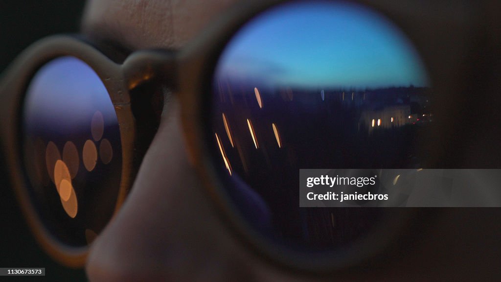 Woman wearing fashionable eyewear. City lights reflecting in glasses