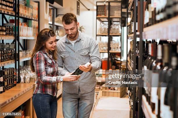 young couple shopping for wine - choosing wine stock pictures, royalty-free photos & images