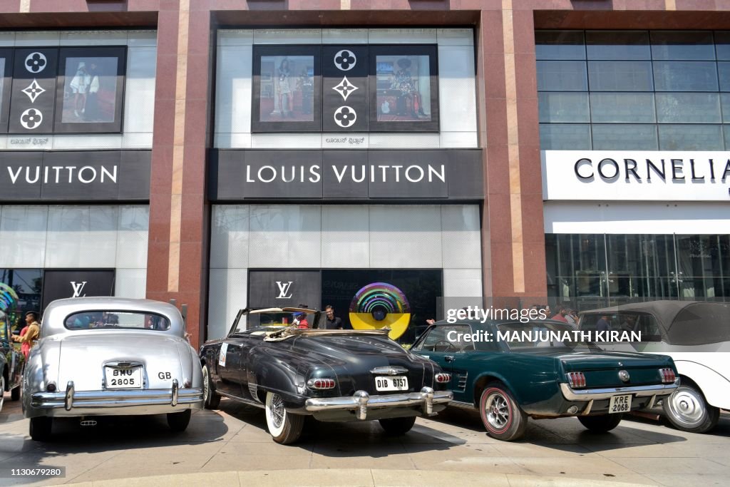 Indian visitors look at vintage cars parked at the UB City Mall