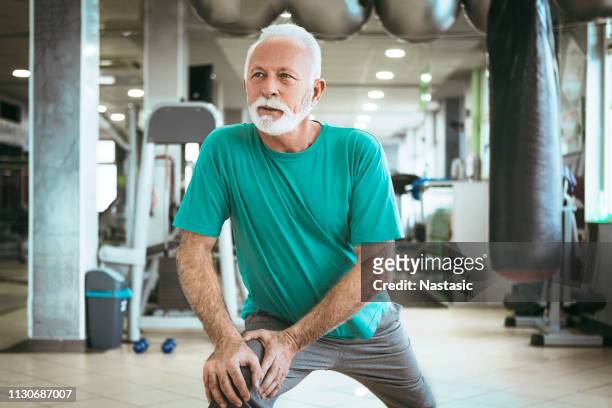 senior man worming up in a gym - circuit training stock pictures, royalty-free photos & images