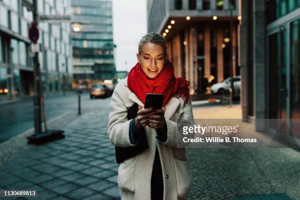 woman smiling while using smartphone - stylish woman streets europe cellphone stockfoto's en -beelden