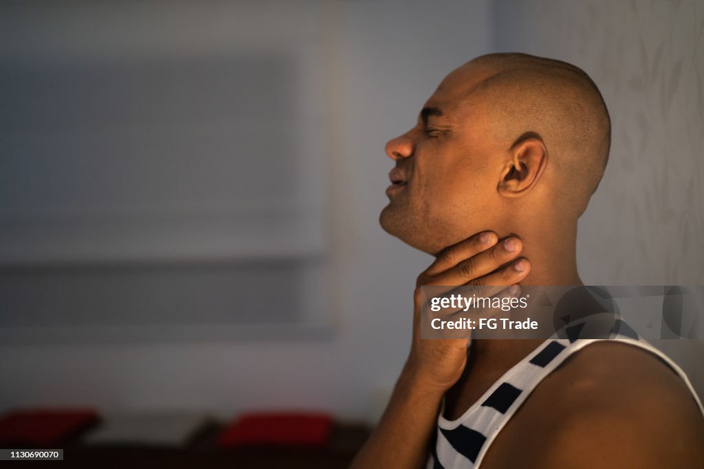 Afro man with sore throat at home