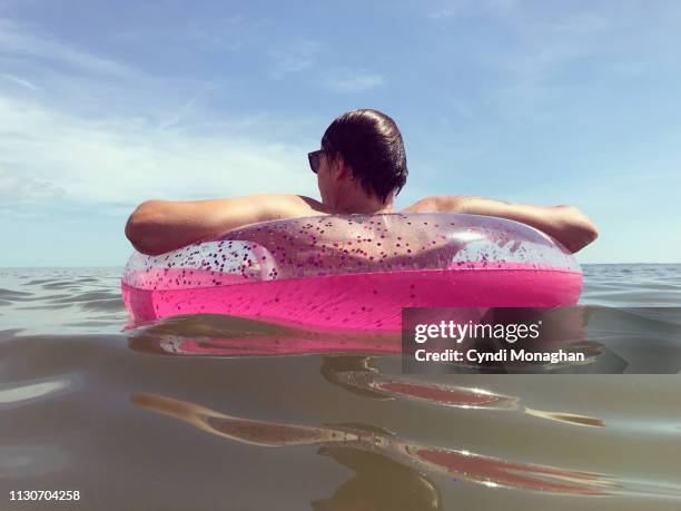 man floating in a pink inner tube in the ocean - eccentric character stock pictures, royalty-free photos & images