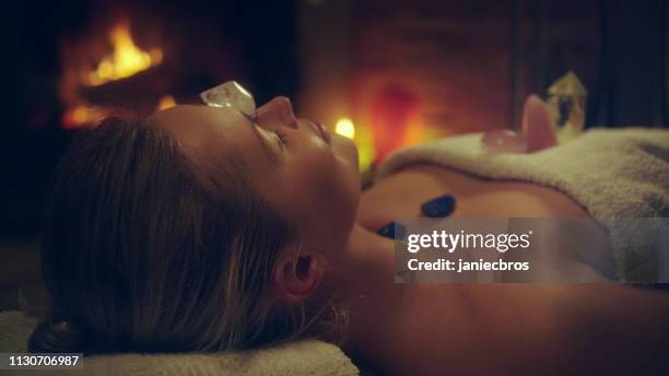 young woman relaxing after crystal healing session. fireplace in background - new age stock pictures, royalty-free photos & images