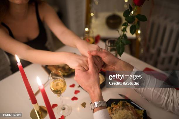 young couple holding hands - valentines day dinner stock pictures, royalty-free photos & images