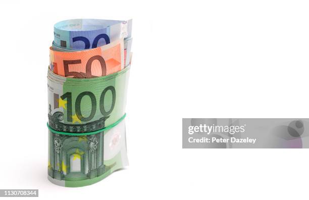 roll of euro notes in elastic band - money roll foto e immagini stock