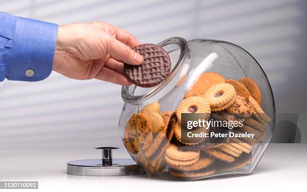 greedy man secretly reaching for chocolate biscuit - cookie jar stock-fotos und bilder