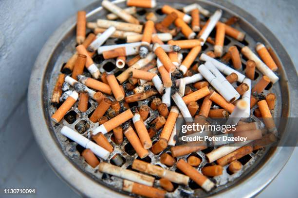 cigarette ends in an outdoor ashtray outside restaurant - stubs stock pictures, royalty-free photos & images