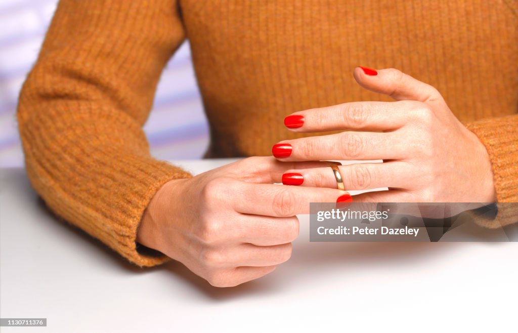Divorced woman taking off wedding ring