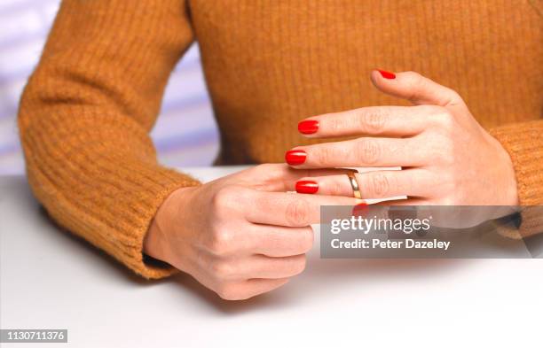 divorced woman taking off wedding ring - divorce photos et images de collection