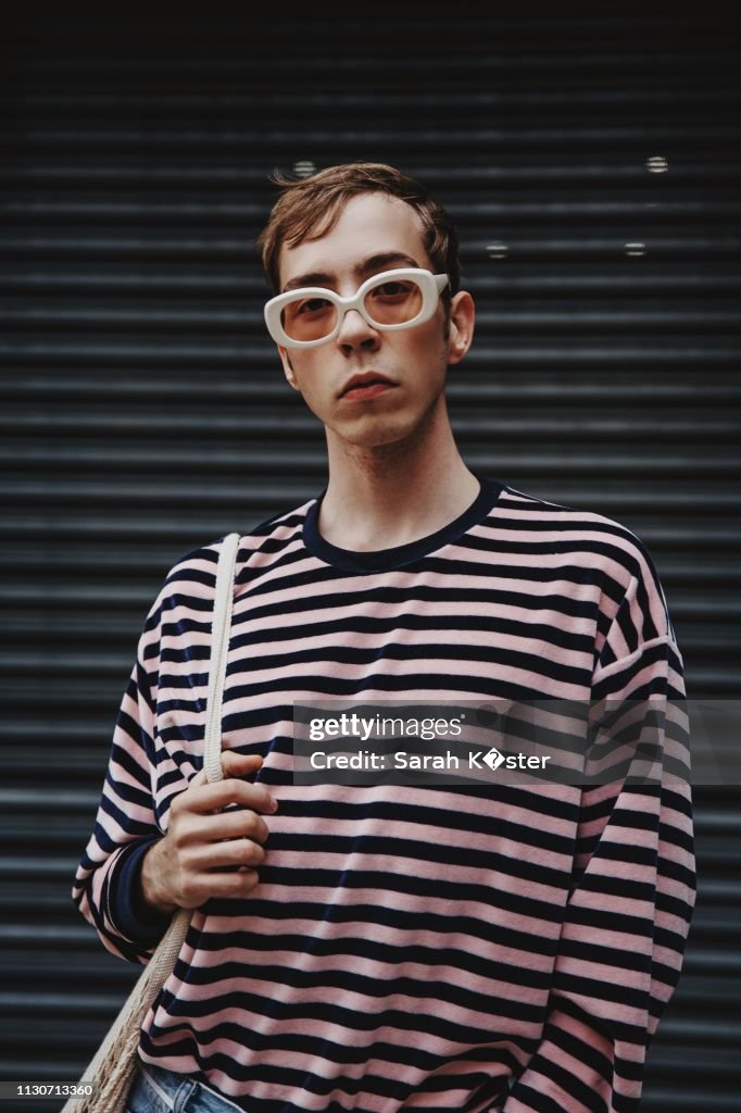 Portrait Of Young Man Wearing Sunglasses While Standing Against Shutter