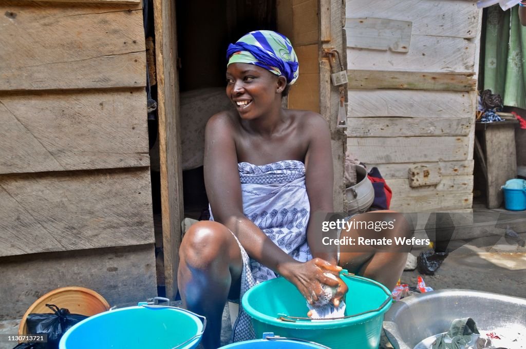 Woman Washing Clothes While Sitting At Entrance