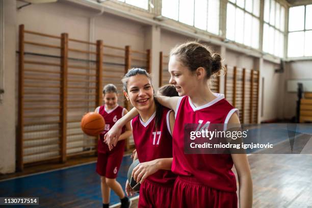 glückliche weibliche spielkameraden im teenageralter - basketballmannschaft stock-fotos und bilder