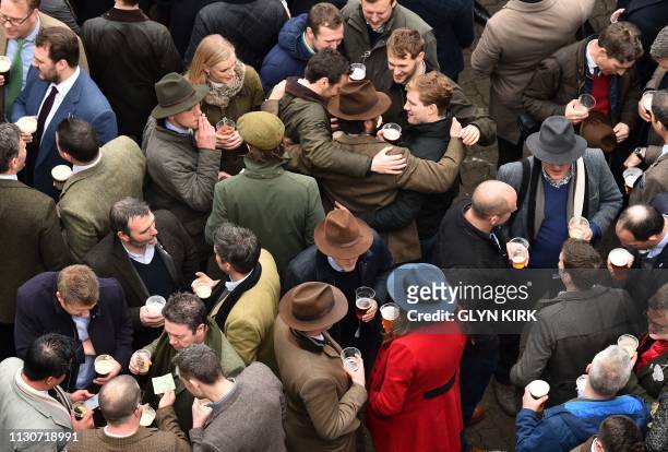 Racegoers enjoy a drink as they attend the final day of the Cheltenham Festival horse racing meeting at Cheltenham Racecourse in Gloucestershire,...