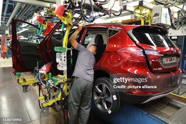 May 2018, North Rhine-Westphalia, Köln: An employee installs a door in a Ford Fiesta at the Ford plant. The US car manufacturer Ford wants to cut...