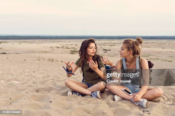 lost friends talking while sitting in desert - fighting stock pictures, royalty-free photos & images