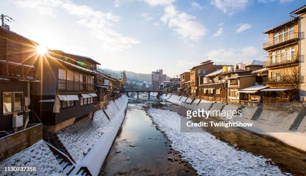 村莊雪日出在高山與紅色木橋和溪水, 日本 - townscape 個照片及圖片檔