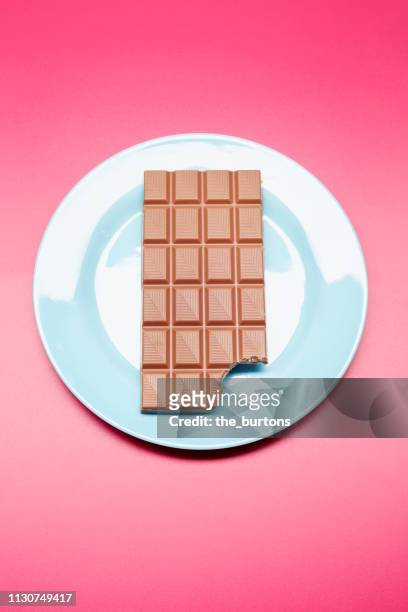 high angle view of chocolate bar on plate on colored background - chocolate ao leite - fotografias e filmes do acervo