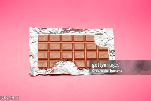 high angle view of chocolate bar on foil and pink background - uppvecklad bildbanksfoton och bilder