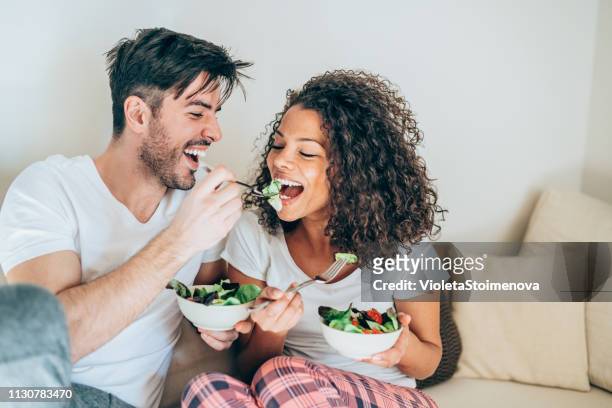 giovane coppia che condivide il cibo - couple eating foto e immagini stock