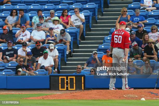 Pitcher Justin Miller of the Washington Nationals gets set to deliver a pitch as the pitch clock counts down against the New York Mets during the...
