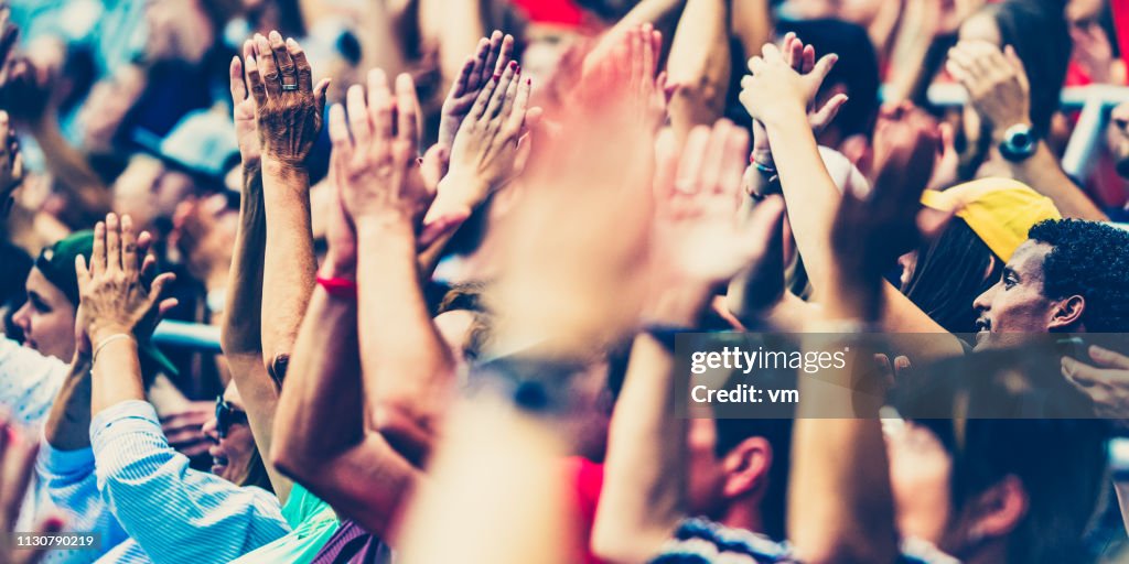 Crowd cheering for their team with arms raised